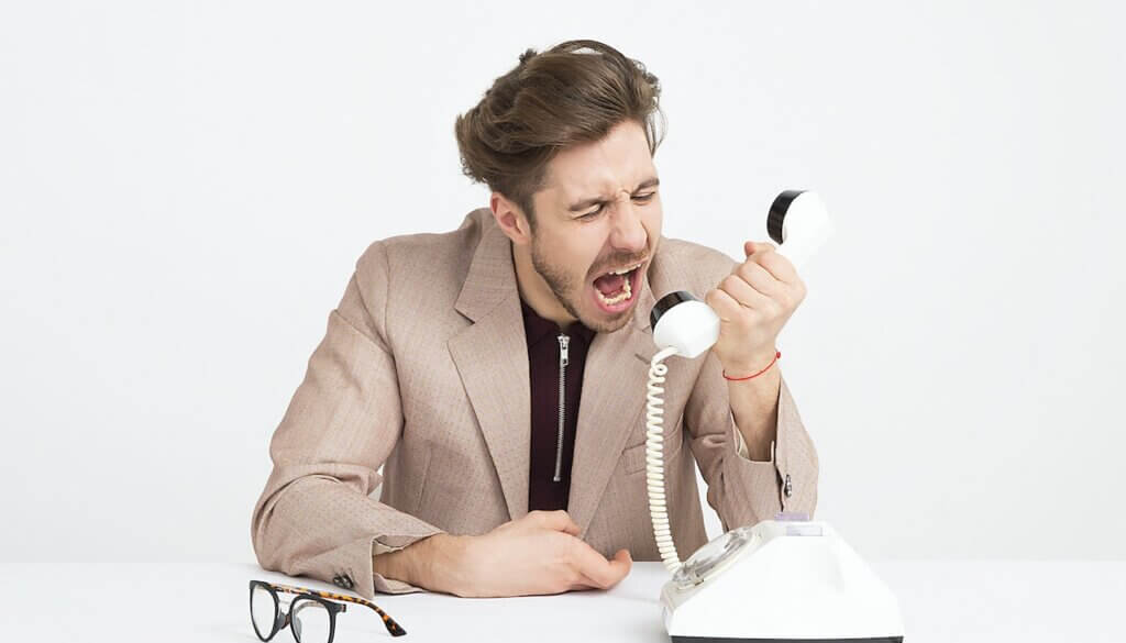Een man spreekt boos aan de telefoon.